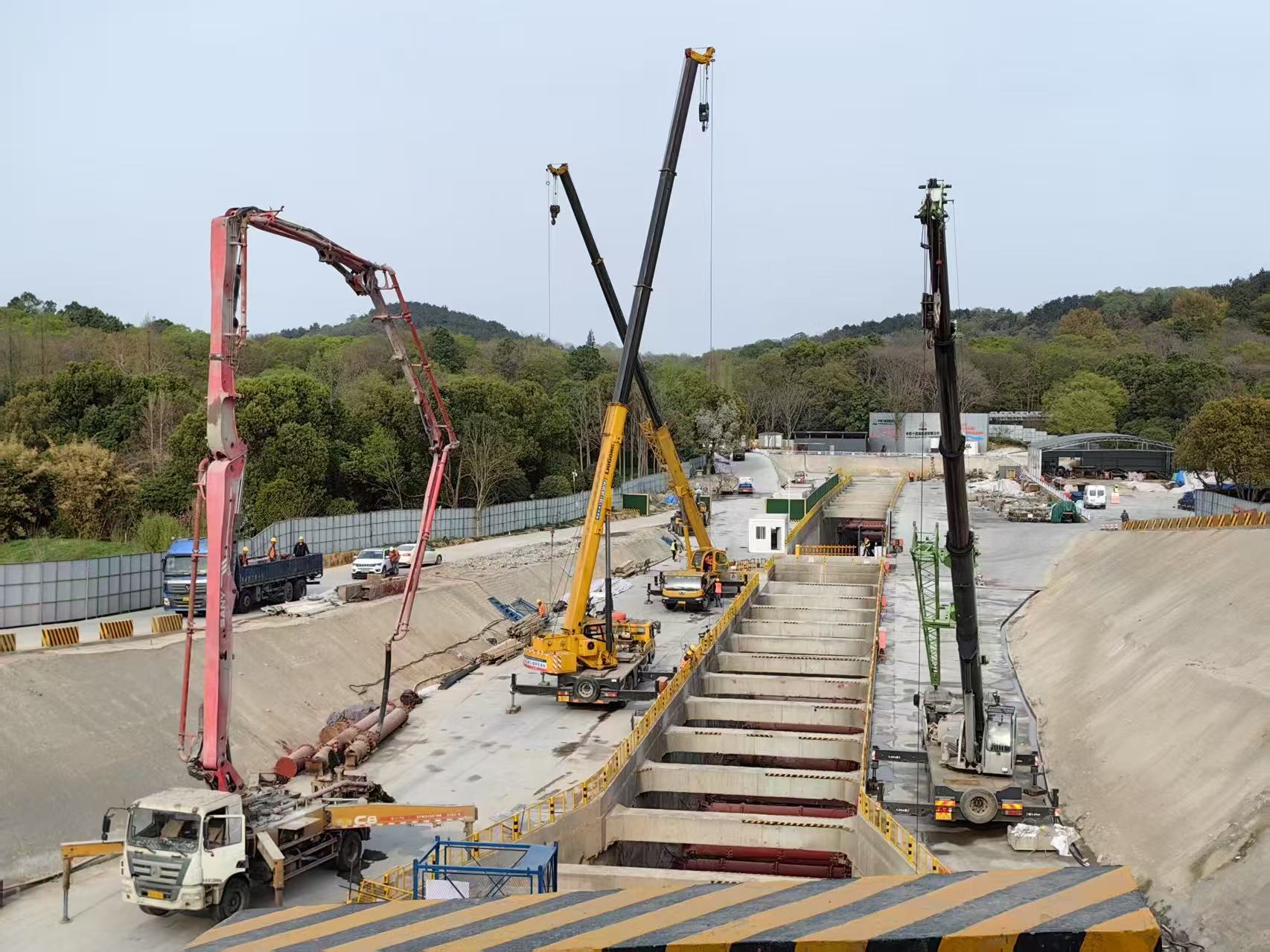 Open-cut high-speed rail tunnel construction with cranes and concrete pump trucks